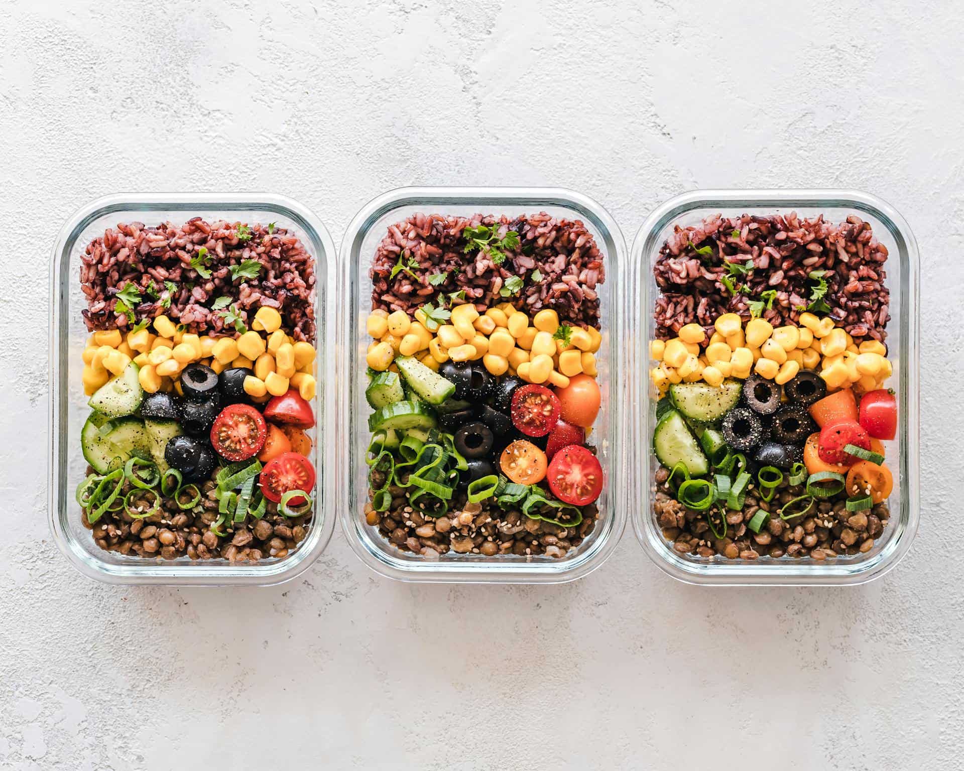 Batch-cooked grains and vegetables in containers.