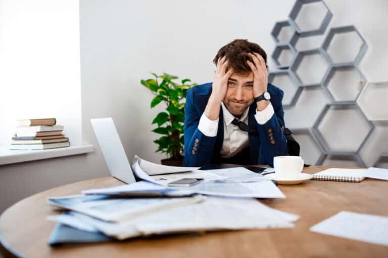 Overwhelmed professional at desk with paperwork, illustrating workplace stress.