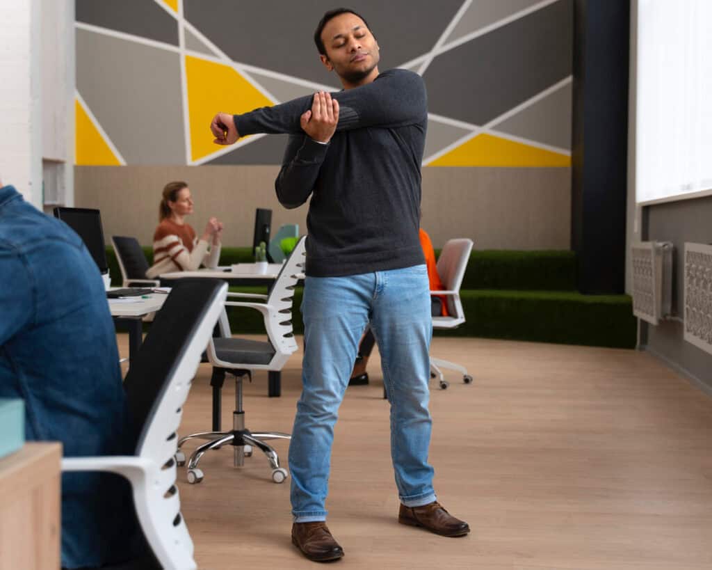 Professional performing a short stretch at their desk to reduce workplace stress.
