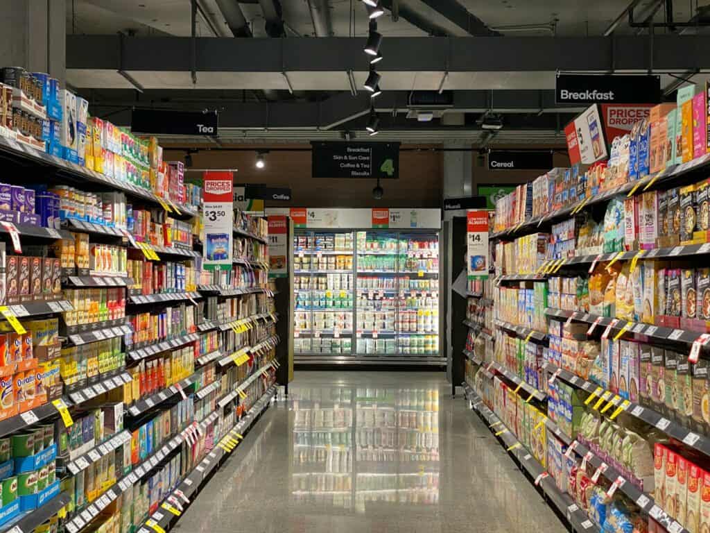 Vegan processed foods in colorful packaging on grocery store shelves.