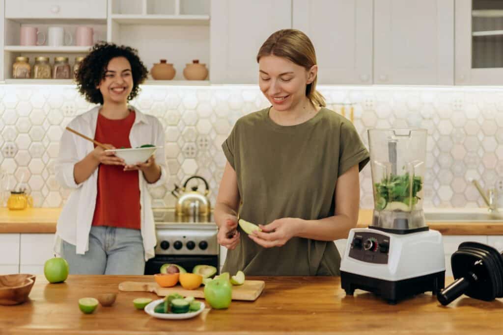 Two friends cooking a healthy meal together, highlighting shared activities that build social connection.